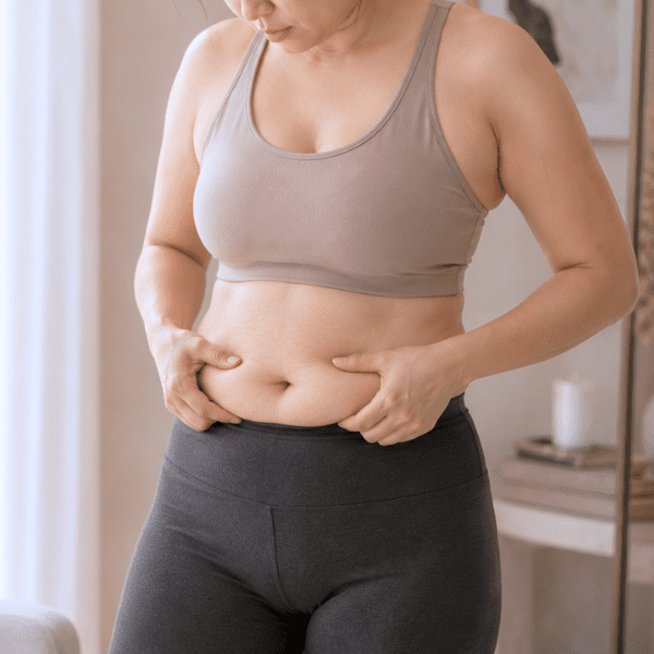 Asian woman checking stubborn fat around her waist.