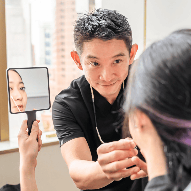 Dr Jonathan Lee conducting a facial assessment during an aesthetic consultation in Singapore